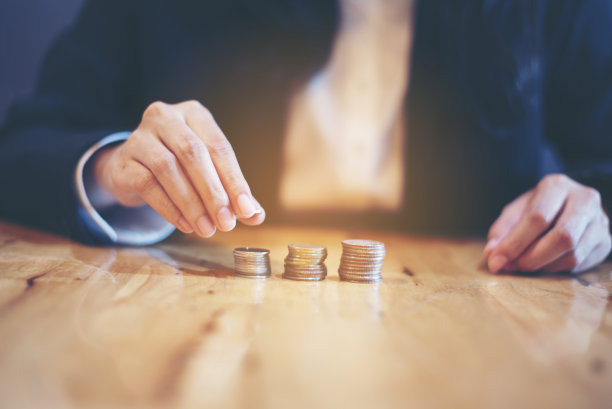 女人手里的存钱罐里有一枚硬币，将来可以用来买房子。省钱。经济的概念图片下载