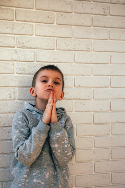 一个穿着灰色衣服的男孩做着乞讨的手势图片下载