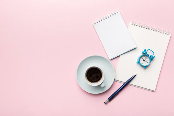现代办公桌上配有笔记本电脑和咖啡杯等用品。空白的笔记本页面为您设计。俯视图，平铺图片下载