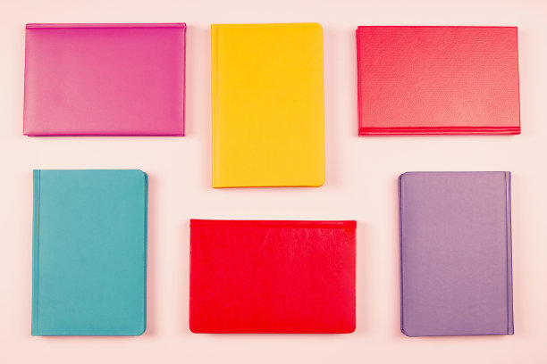 彩色精装书排列在粉彩粉色的背景。俯视图图片下载