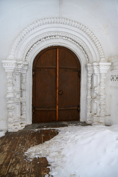 巨大的拱形木门，由带半柱的带图案的石头框架构成。特写镜头。图片下载