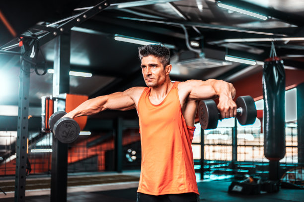 运动成熟男子做手臂运动。肌肉健美模特在健身房用哑铃锻炼的照片。力量和动力图片下载