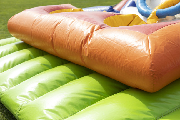 绿色的蹦床。充气滑梯。超越障碍训练场。娱乐公园。图片下载