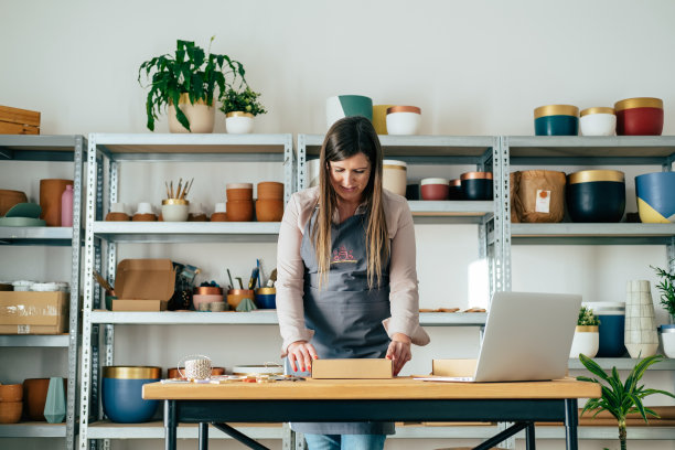 低角度的观点微笑的女人在围裙准备圣诞节的装饰品粘土交付在她的商店图片下载