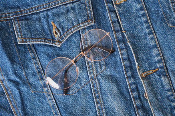 蓝色牛仔夹克口袋上的圆形金属镜框眼镜，潮流眼镜，复古风格图片下载