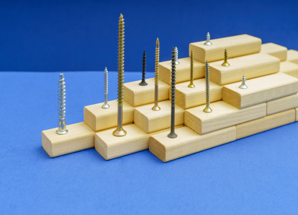 各种形状、颜色、大小的螺丝放在蓝色背景的木条上图片下载