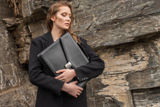 年轻女人穿着西装，拿着公文包。女商人，穿着时髦休闲的办公室服装。图片下载