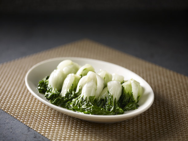 水煮婴儿卷心菜在一个盘子孤立在垫子侧视图在黑暗的背景图片下载