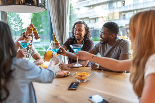 在一个炎热的夏夜，在新房子里与快乐的朋友举杯。国际多元化的民族。图片下载