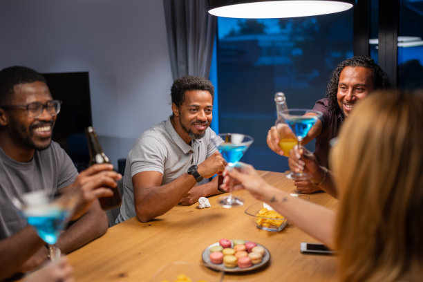 在一个炎热的夏夜，在新房子里与快乐的朋友举杯。国际多元化的民族。图片下载