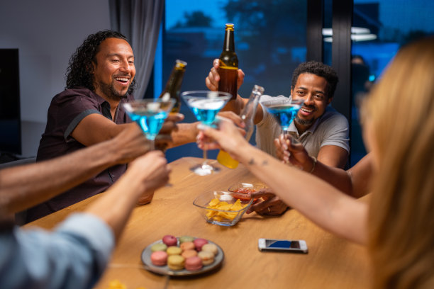 在一个炎热的夏夜，在新房子里与快乐的朋友举杯。国际多元化的民族。图片下载