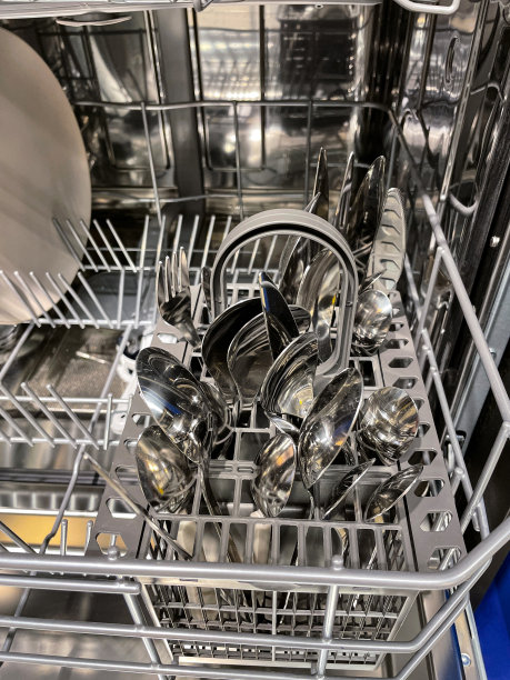 塑料洗碗机内部图像，餐具篮内盛有干净的不锈钢刀、叉和匙，机器半满，清洗和烘干后可收纳干净的餐具图片下载