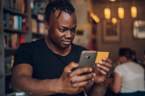 非洲裔美国人在咖啡馆使用智能手机和信用卡图片下载