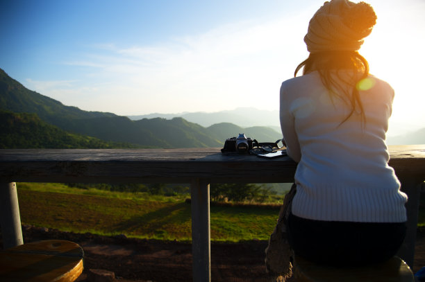 亚洲女性喝咖啡与山景在日落，在早上拍照，放松和坐在户外茶园在阳光下享受她的生活。图片下载
