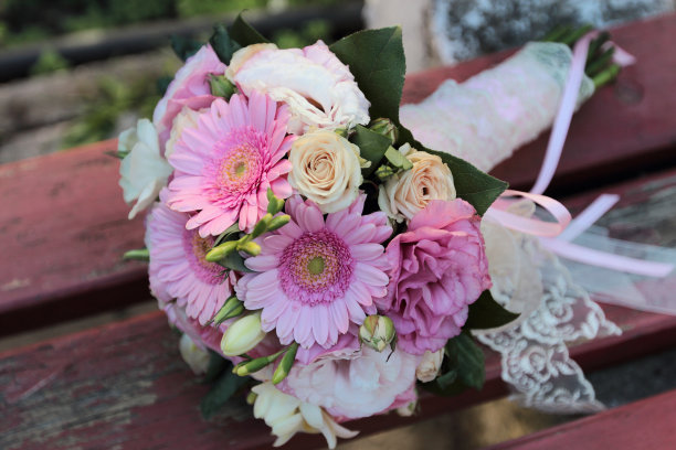 美丽多彩的花束，婚礼花束由白色，粉色，紫色的花朵，绿色的叶子，非洲菊花，牡丹玫瑰在旧的木制背景与剥落的红色油漆图片下载