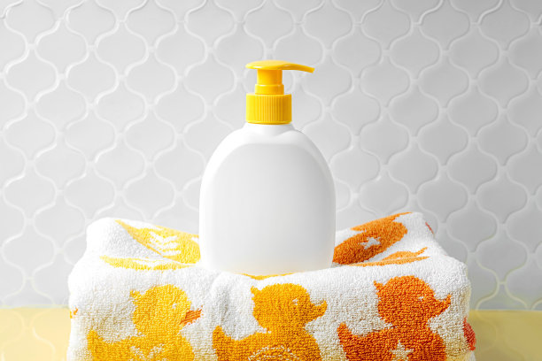 肥皂或洗发水瓶子和婴儿毛巾与可爱的鸭子在黄色的背景。沐浴配件图片下载