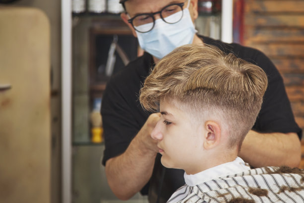 有型的理发师给一个年轻人剪了一个时髦的发型。人们在工作中。小型企业或服务概念。在理发店或发廊专业理发和造型图片下载