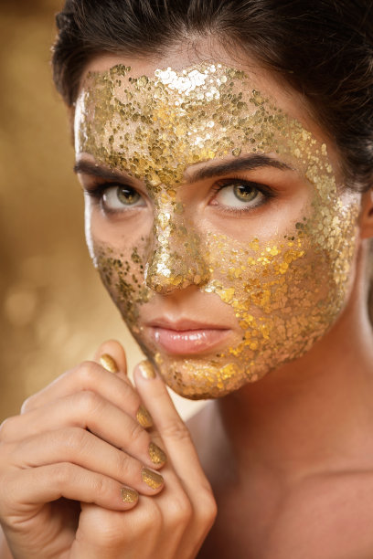 美丽的女人，脸上敷着金光闪闪的面膜，用于皮肤护理图片下载