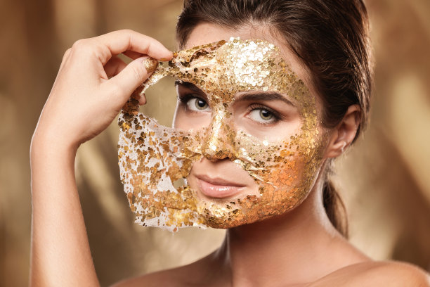 美丽的女人，脸上敷着金光闪闪的面膜，用于皮肤护理图片下载