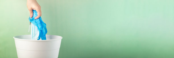 医疗废物回收，环保，护士的手把用过的注射器、口罩、医用手套扔进垃圾桶，横幅以绿色为背景图片下载