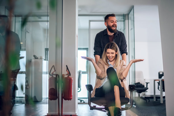 同事们在办公室的椅子上比赛，笑着玩图片下载