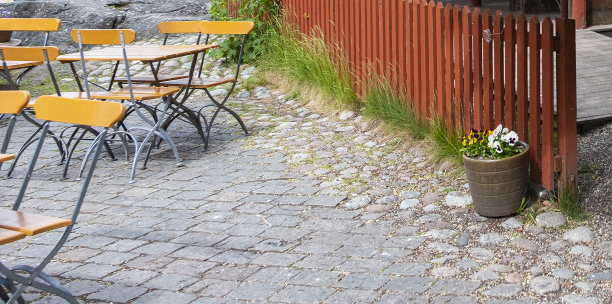 瑞典乡村咖啡馆的桌椅，铺路石，木栅栏和花坛。图片下载