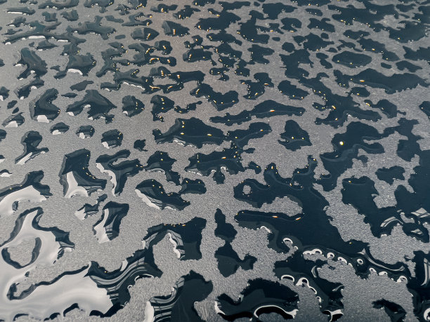 雨滴在黑色的桌子表面，形成一些抽象的概念背景图片下载
