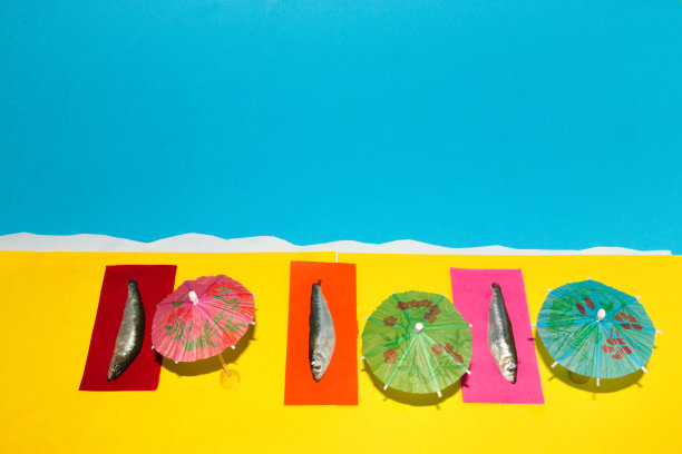 三条鱼坐在五颜六色的躺椅上享受阳光灿烂的日子，在沙滩上晒太阳，抽象出田园诗般的场景图片下载