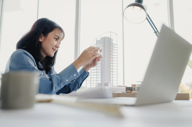选择重点，亚洲女性建筑师或工程师目前正在考虑设计现代公寓的材料。亚洲女性建筑师或工程师坐在办公室里分析、设计项目图片下载