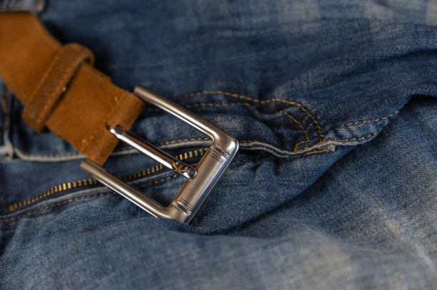 蓝色牛仔裤。摩擦休闲裤与棕色皮带。闪亮的银扣。特写镜头。有选择性的重点。图片下载