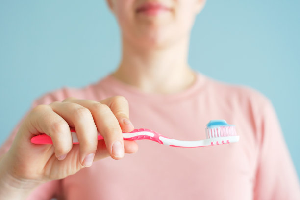 女孩拿着牙刷和牙膏在蓝色的背景，选择性聚焦。图片下载