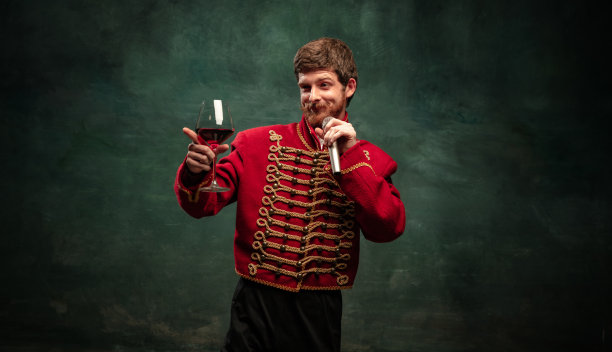 英俊的年轻人在中世纪骠骑兵的形象中孤立地摆出深蓝色的背景。复古的风格，比较时代的概念。图片下载