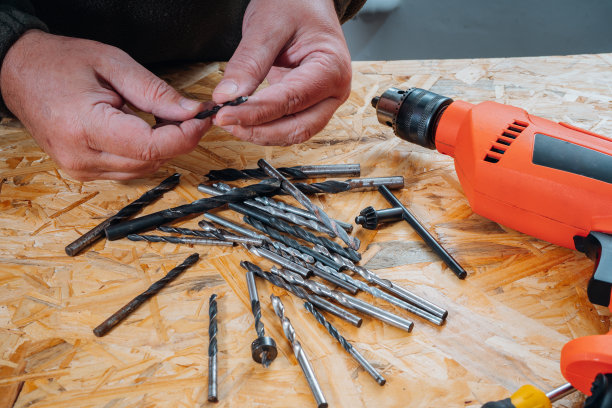 工人在工作台上从一组不同的钻头中选择钻头。图片下载