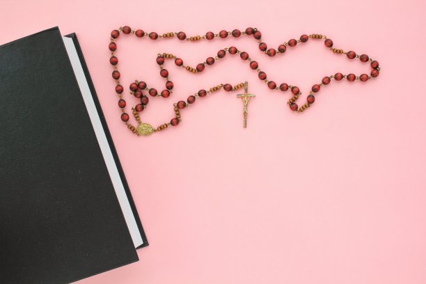念珠和十字架基督十字架上神圣的圣经书与复制空间的文字在粉红色的背景图片下载