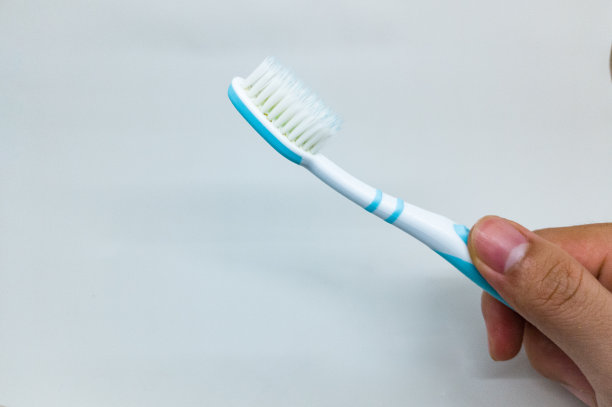 在白色的背景上，一个成年人的旧绿松石牙刷和一个男人的手图片下载