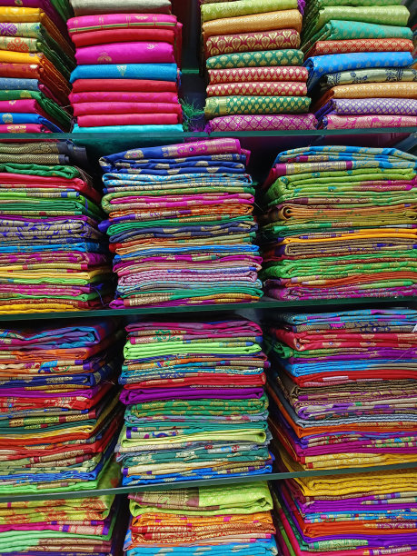 近距离观察堆叠的颜色纱丽或纱丽展示在印度零售商店，纺织商店。图片下载