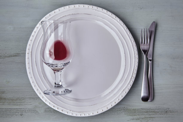 蓝色的木桌上放着白色的盘子和餐具，还有一杯酒图片下载