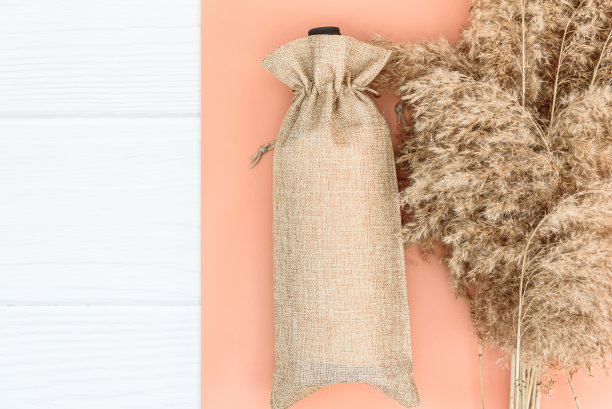 秋季模型与酒袋空白和干燥的芦苇在白木背景。图片下载