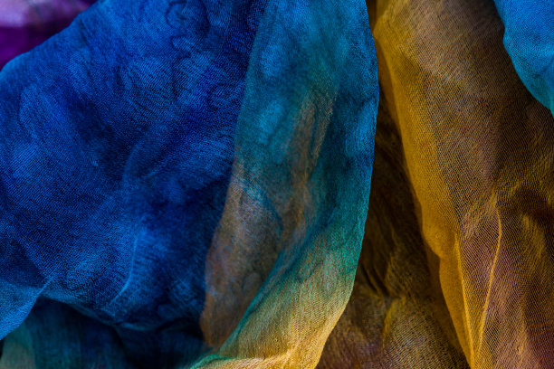 织物染成蓝色和黄色和少量紫色的俯视图照片，并以抽象形式作为背景。图片下载