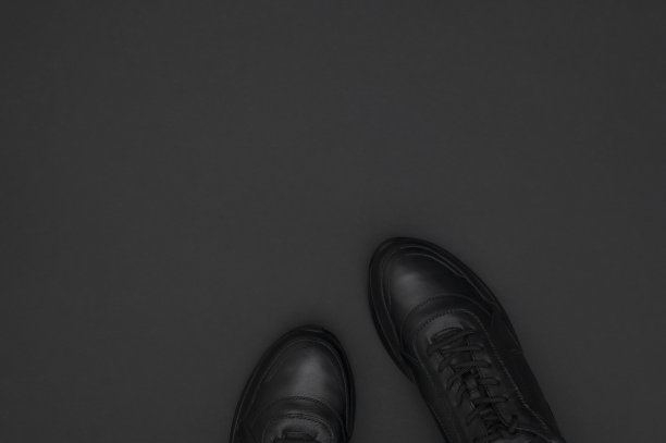 扁平的黑色经典皮革男子运动鞋在黑色背景。时尚青年运动运动鞋。运动休闲鞋顶视图拷贝空间。鞋类健身，跑步，健康的生活方式图片下载