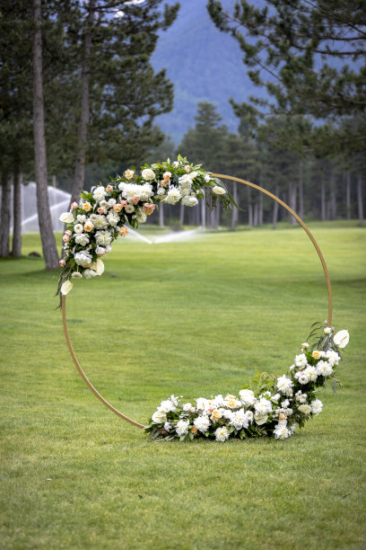 绿色的草坪上点缀着鲜花的婚礼拱门图片下载