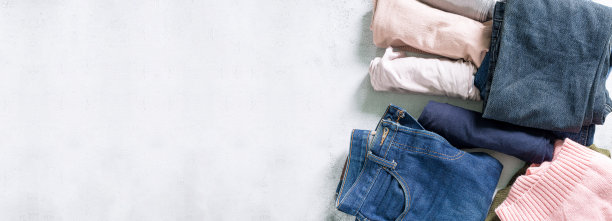 衣服和牛仔裤，一堆五彩缤纷的完美折叠的衣服。堆不同的粉彩衬衫，毛衣孤立和其他服装在白色的背景。关闭，复制空间。图片下载