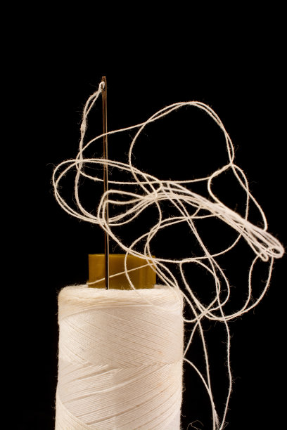 针、白棉、缠纱卷上缝制。用于织物和纺织工业的线。黑色背景图片下载