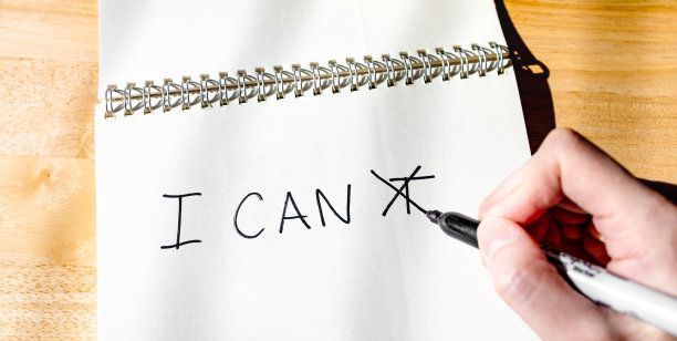 一个人在写单词I CAN'T时，在字母T上交叉了线。图片下载