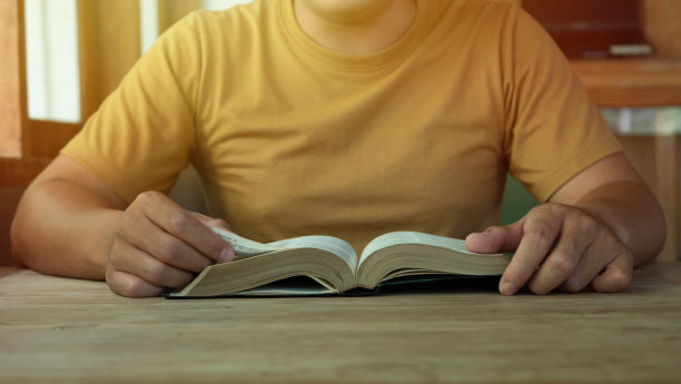 一个男人在有窗光的木桌上手持圣经，危机解决祈祷上帝，基督徒的信仰，信任和服从，晨祷的理念与拷贝空间图片下载