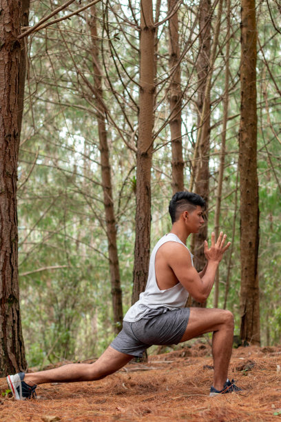 运动员练习瑜伽的垂直照片战士的姿势。健康的生活方式。年轻人在树的背景下做伸展运动。图片下载