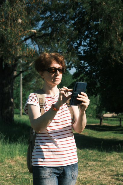 疲惫成熟的女人站在乡村的街道上，用手机定位图片下载