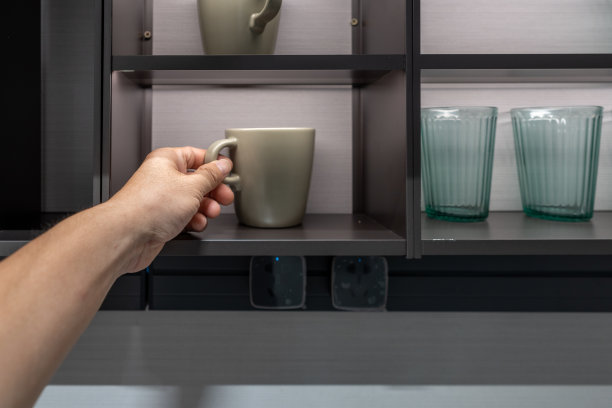 一只手拿着杯子在餐厅的厨房橱柜里图片下载
