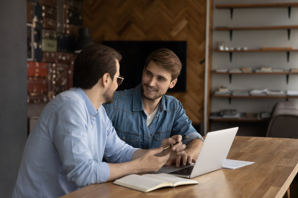 快乐的男同事在办公室的笔记本电脑上合作图片下载