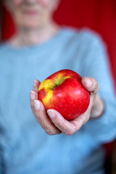 老妇人拿着红苹果的特写图片下载